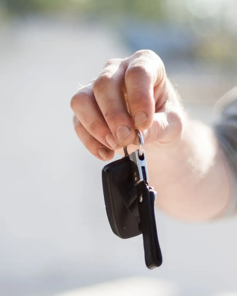 A hand holding out a car key.